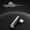 A Ugreen USB-C to 3.5mm audio adapter is shown on a textured dark surface, with abstract sound wave graphics in the background. Podgląd zdjęcia produktu