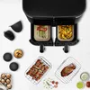 A top-down view of a dual-basket air fryer with food in both baskets, surrounded by various accessories and food items. Anteprima dell’immagine prodotto