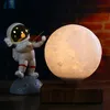 An astronaut figurine playing a violin next to a levitating moon lamp. Produktbild-Vorschau