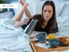 A woman is lying in bed, pouring coffee from a moka pot into a mug, with a breakfast tray nearby. Produktbild-Vorschau