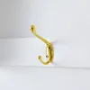 A close-up shot of a gold-colored hook attached to a white surface. Produktbild-Vorschau