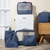 A set of blue packing cubes and bags are arranged around a white suitcase. Anteprima dell’immagine prodotto