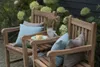 Two wooden garden benches with cushions and a small table with a slice of cake and a mug. Produktbild-Vorschau