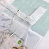 A close-up view of a transparent curtain with embroidered details, layered over a magazine or brochure with text. Produktbild-Vorschau