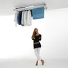 A woman stands looking up at a ceiling-mounted clothes drying rack. Produktbild-Vorschau