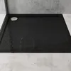 A black shower tray with a textured surface and a silver drain cover, placed on a light gray tiled floor with a concrete wall in the background. Produktbild-Vorschau