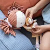 A person's hands are holding a small monkey plush toy next to a larger doll. Produktbild-Vorschau