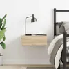 A floating nightstand with a lamp and a cup on it, next to a bed. Produktbild-Vorschau