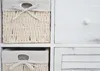 A close-up view of a white wooden dresser with woven baskets as drawers. Produktbild-Vorschau