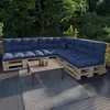 An outdoor seating area with a sectional sofa made of wooden pallets and dark blue cushions, a coffee table, and a rug on a deck, surrounded by trees. Anteprima dell’immagine prodotto