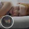 A child sleeping peacefully next to a clock mechanism. Voir les images du produit