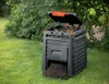 A black compost bin with an open lid, sitting on a green lawn next to a bush. Compost is spilling out of the bottom. Náhled obrázku produktu