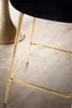 Close-up of the gold legs of a bar stool with a black seat. Voir les images du produit