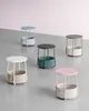 Five side tables with fabric baskets in various colors are arranged on a concrete floor against a pink wall. Náhled obrázku produktu