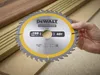 A hand holding a Dewalt circular saw blade over pieces of wood. Náhled obrázku produktu