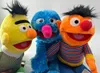 A close-up shot of three Sesame Street plush toys: Bert, Grover, and Ernie. Produktbild-Vorschau
