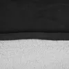 A close-up view of the fabric texture of a blanket hoodie, showing the black outer layer and the light gray inner lining. Náhled obrázku produktu