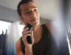 A man is shaving his face with an electric razor. Podgląd zdjęcia produktu