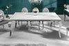 A modern dining table with a marble-effect top and chrome legs, set in a dining room with upholstered chairs and a chandelier. Náhled obrázku produktu