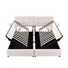 A white upholstered bed frame with its hydraulic lift mechanism and wooden slats exposed, shown against a white background. Produktbild-Vorschau
