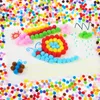 A flat lay image showing a collection of colorful pom poms arranged to create crafts on a white surface, surrounded by more pom poms. Produktbild-Vorschau