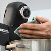 A person is cleaning a kitchen appliance with a cloth. Produktbild-Vorschau