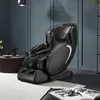 A black massage chair is placed in a modern living room setting, next to a small coffee table with a coffee maker and cups. Produktbild-Vorschau