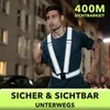 A man is running at night in a city street, wearing a reflective vest. Produktbild-Vorschau
