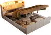 A white storage bed with its mattress lifted to reveal storage compartments filled with folded linens and other items. The headboard has integrated lighting and shelves. Anteprima dell’immagine prodotto