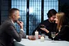 A romantic dinner scene with three people at a table with candles and drinks. Podgląd zdjęcia produktu