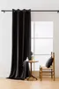 A black velvet curtain hangs on a rod next to a window. A small wooden table with a decorative item and a plant sits in front of the curtain, and a wooden chair with a black cushion is to the right. Produktbild-Vorschau