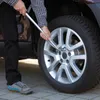 A person is changing a car tire using a lug wrench. Produktbild-Vorschau