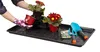 Hands wearing gardening gloves are shown planting flowers into a tray. Produktbild-Vorschau