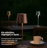 Three battery-powered table lamps are displayed on a table outdoors at dusk, with a cup and saucer in the foreground. Podgląd zdjęcia produktu