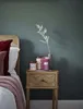 A bedside table with candles and a decorative branch next to a bed. Produktbild-Vorschau