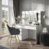 A modern white vanity table with illuminated mirror, a grey chair, and decorative elements in a well-lit room. Náhled obrázku produktu
