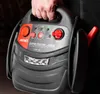 A person is holding a black and red jump starter device. Podgląd zdjęcia produktu