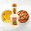 A bottle of almond extract is shown next to a bowl of almonds and a small dish of almond oil. Voir les images du produit