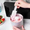 A person is using an ice cream maker to scoop pink ice cream into a container. Náhled obrázku produktu