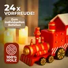 A close-up of a red wooden toy train advent calendar with gold accents, set against a blurred background of lit candles. Produktbild-Vorschau