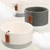 Three ceramic pots of varying sizes are displayed against a light background with soft, fluffy white elements suggesting clouds or cotton. Podgląd zdjęcia produktu