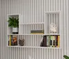 A white wall-mounted shelf unit with books, a plant, and a decorative item. Voir les images du produit