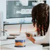 A person is working at a desk with a computer and a spindle of DVDs. Produktbild-Vorschau