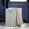 A laundry basket with clothes in it, placed on a rug in front of a blue cabinet. Náhled obrázku produktu