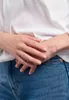 A close-up shot of a person's hands wearing a ring, with their hands resting on their lap. Anteprima dell’immagine prodotto