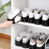 A white shelf with multiple black shoe organizers holding pairs of sneakers. Produktbild-Vorschau