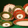 A collection of Christmas-themed plates arranged on a green background. Anteprima dell’immagine prodotto