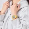 A person wearing a grey hoodie and a gold digital watch. Produktbild-Vorschau