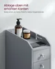 A close-up of a gray bathroom cabinet with two drawers and a shelf on top, featuring a soap dispenser and a jar. Text overlays describe the shelf's features and dimensions. Produktbild-Vorschau