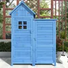 A blue wooden garden shed with a pitched roof and a window, set outdoors on a patio with plants and a trellis in the background. Voir les images du produit